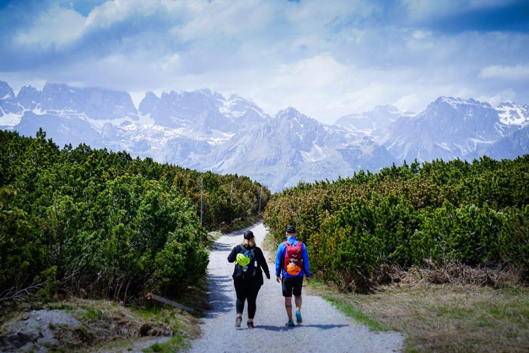 Man and woman hiking along a path on Paganella Mountain in Trentino Italy