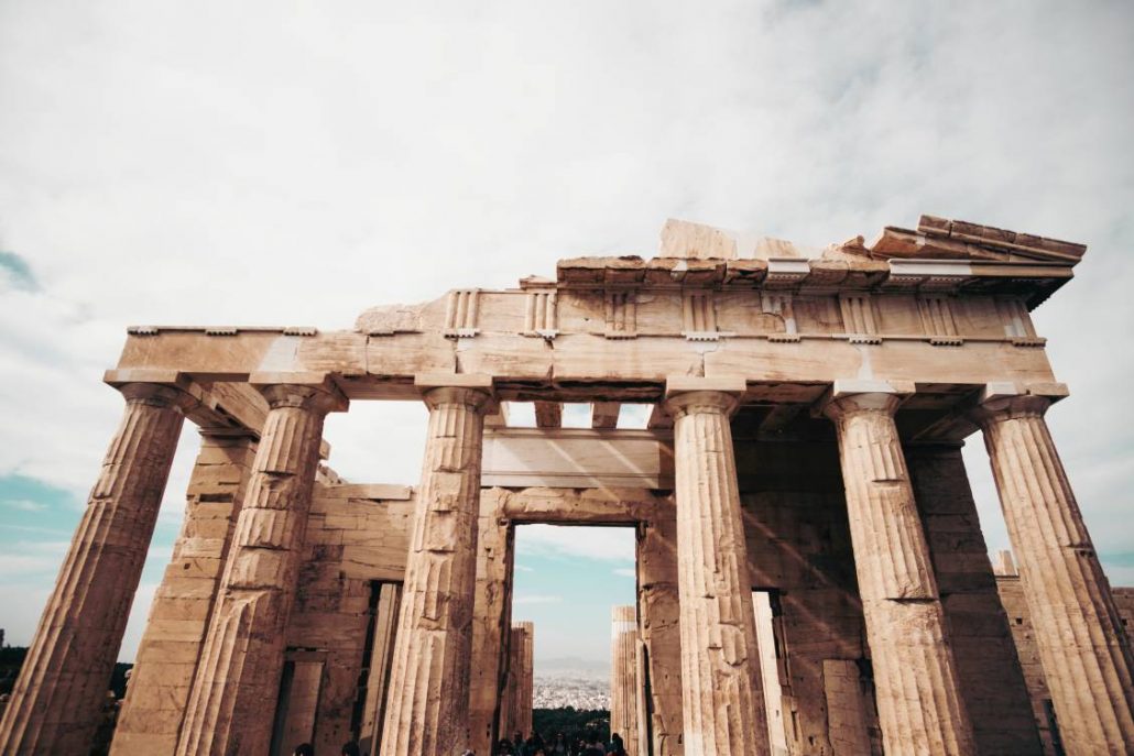 Photo of the ancient Acropolis of Athens featuring the ruins of 6 Doric columns in the forefront.