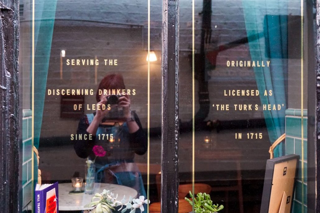 Reflection of Alice Teacake in the window of Whitelocks pub as she takes a photo outside of it