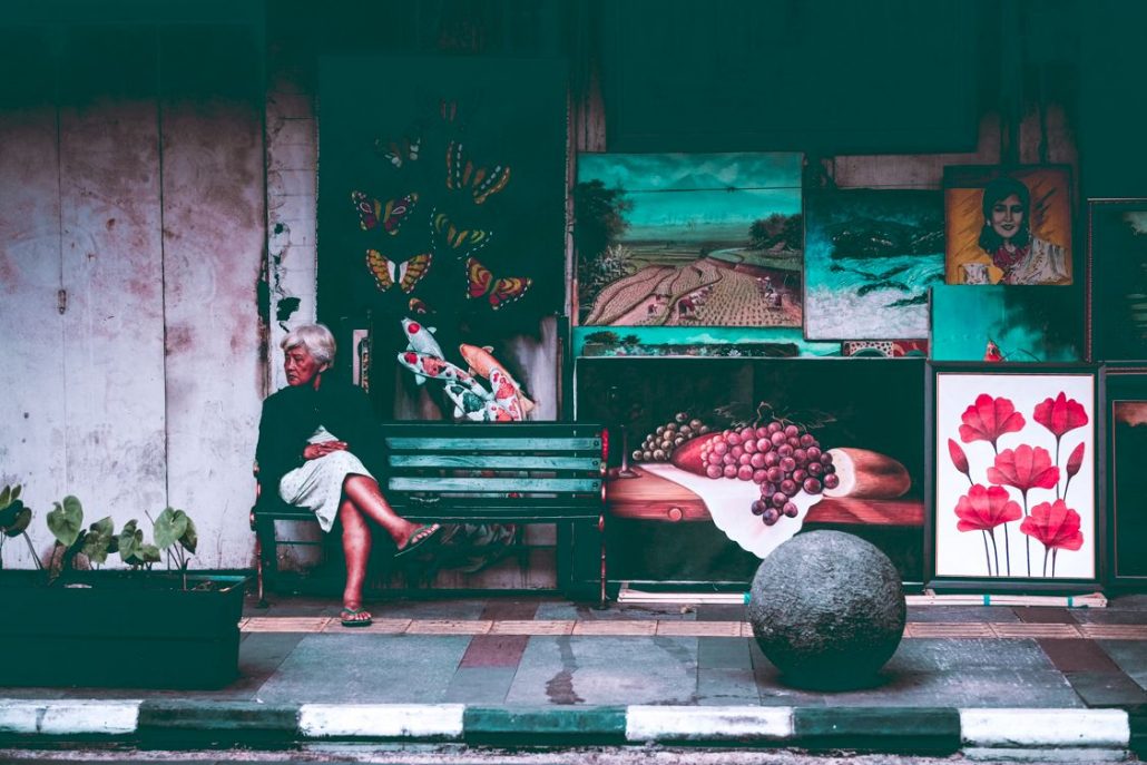 Local lady sitting on a bench chilling out in front of a shop on the streets of Bandung