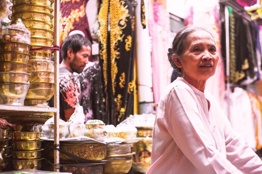 An old lady wearing pink and selling her goods in a very busy Beringharjo Market, Yogyakarta, Indonesia