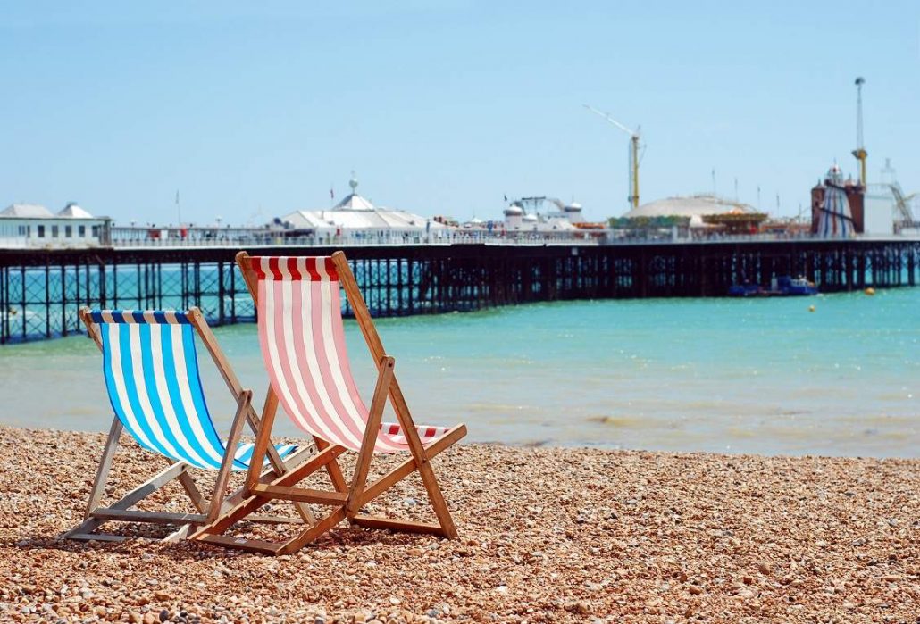 A red and blue deckchair on Brighton Beach looking out to Brighton Pier