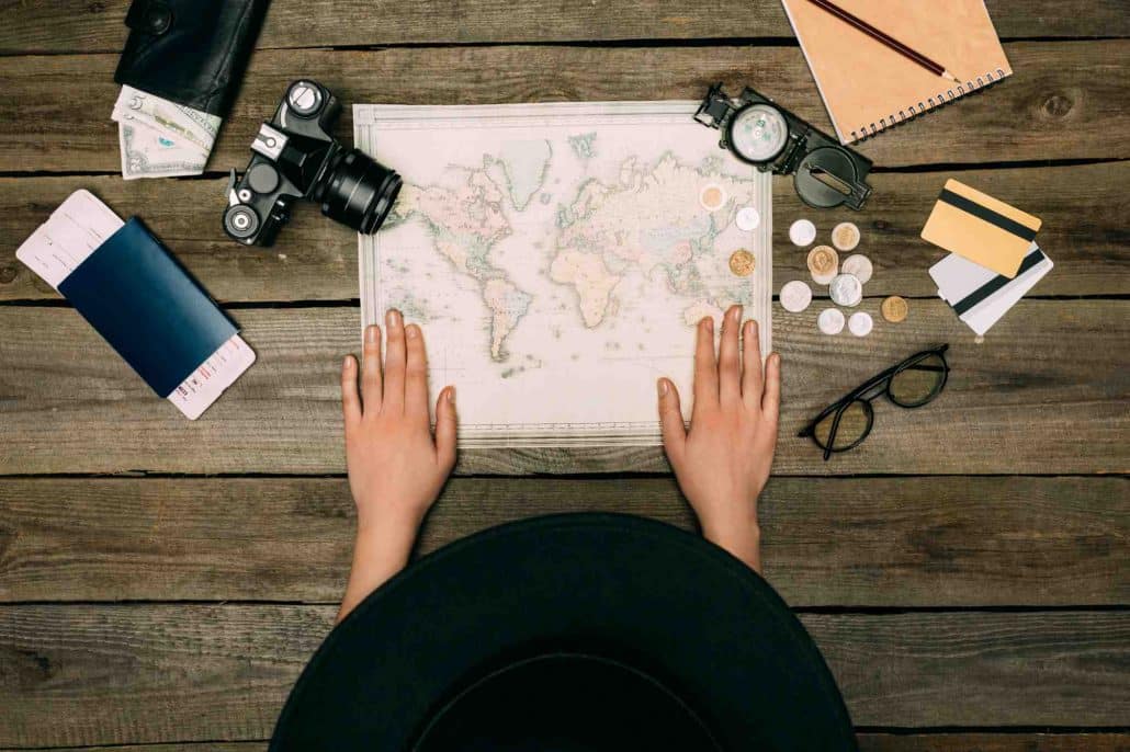 A bird's eye view of a woman looking at a map, a camera and some leftover currency