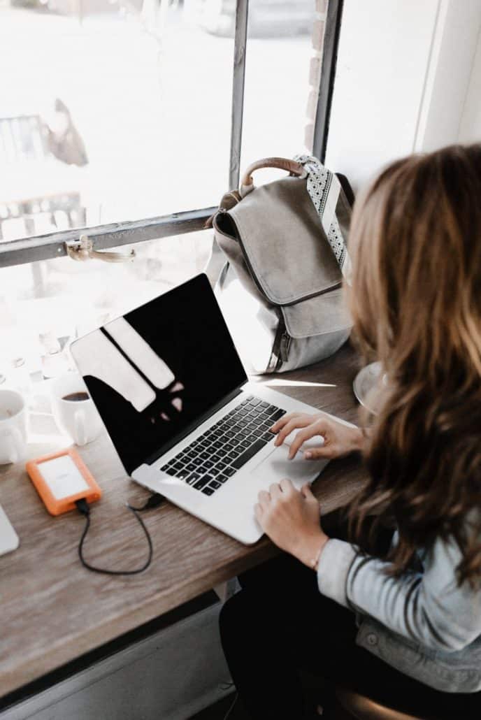 Girl working on laptop in front of window