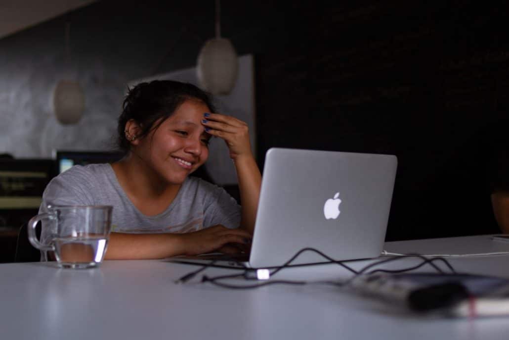 A smiling woman using a Macbook