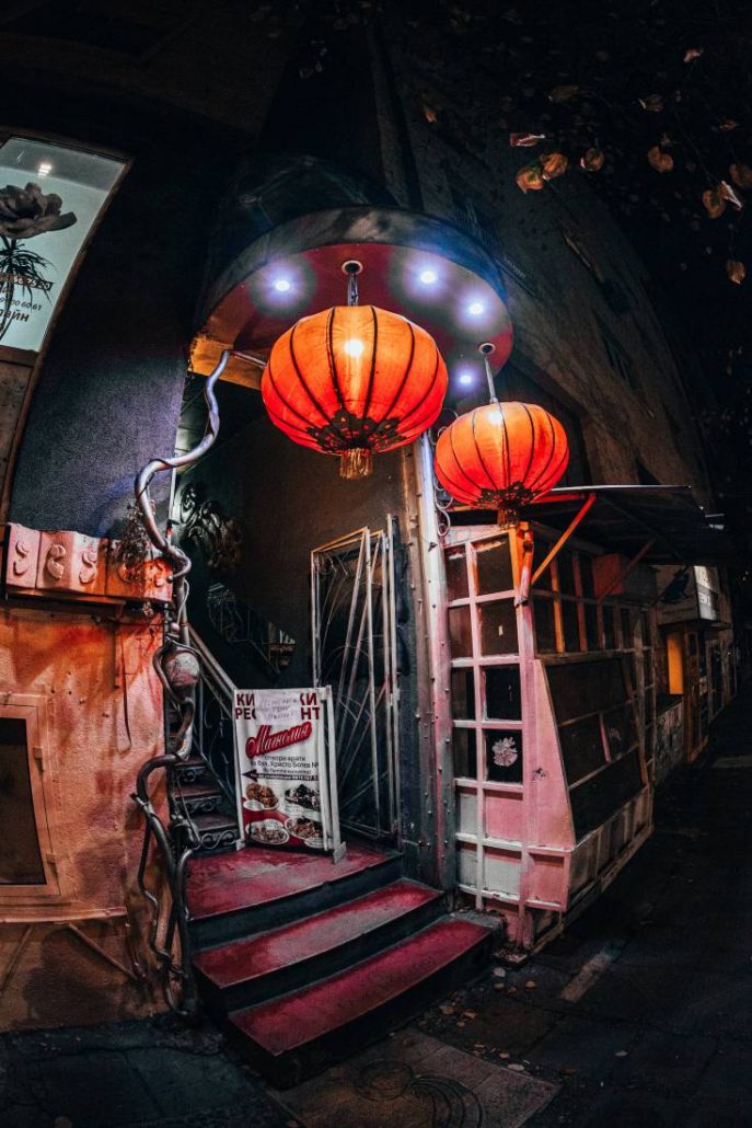 Photo of a modest restaurant entrance at night featuring two illuminated red lanterns in Sofia, Bulgaria.