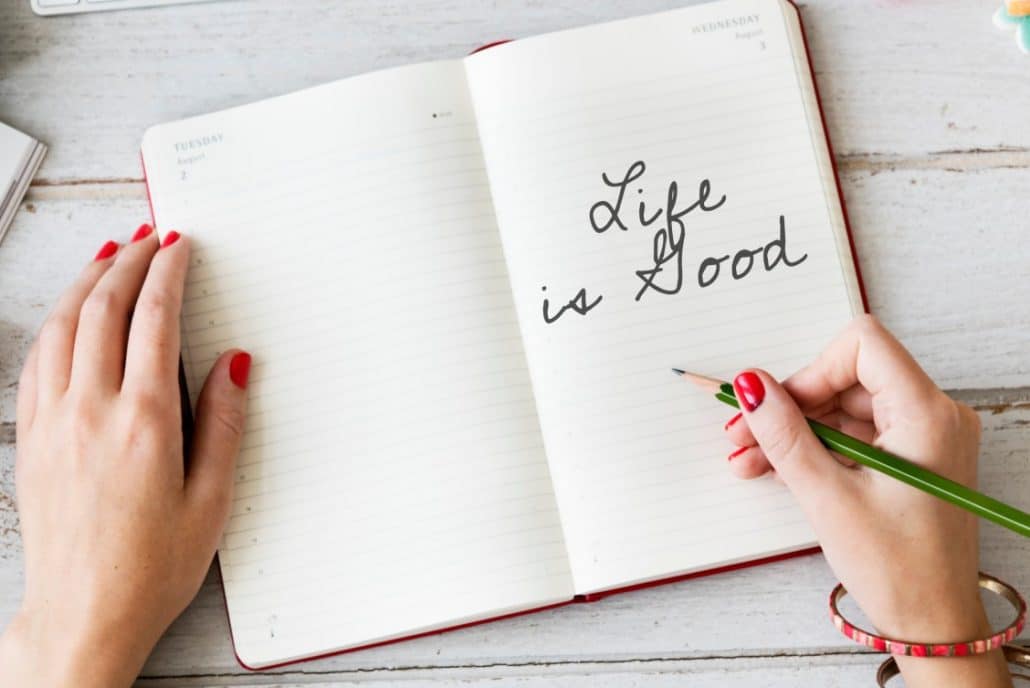 A birds' eye view of a lady writing in her travel journal with the words 'Life is Good'