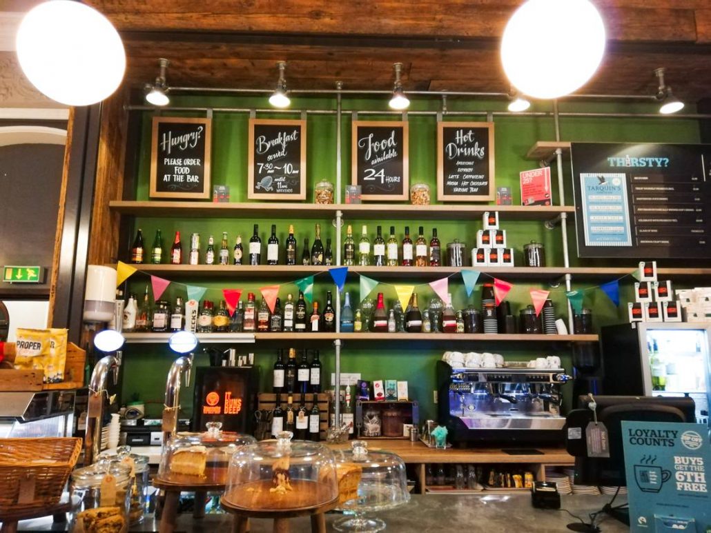 Green bar stacked with drinks, fun chalkboards and colourful flags at YHA Brighton