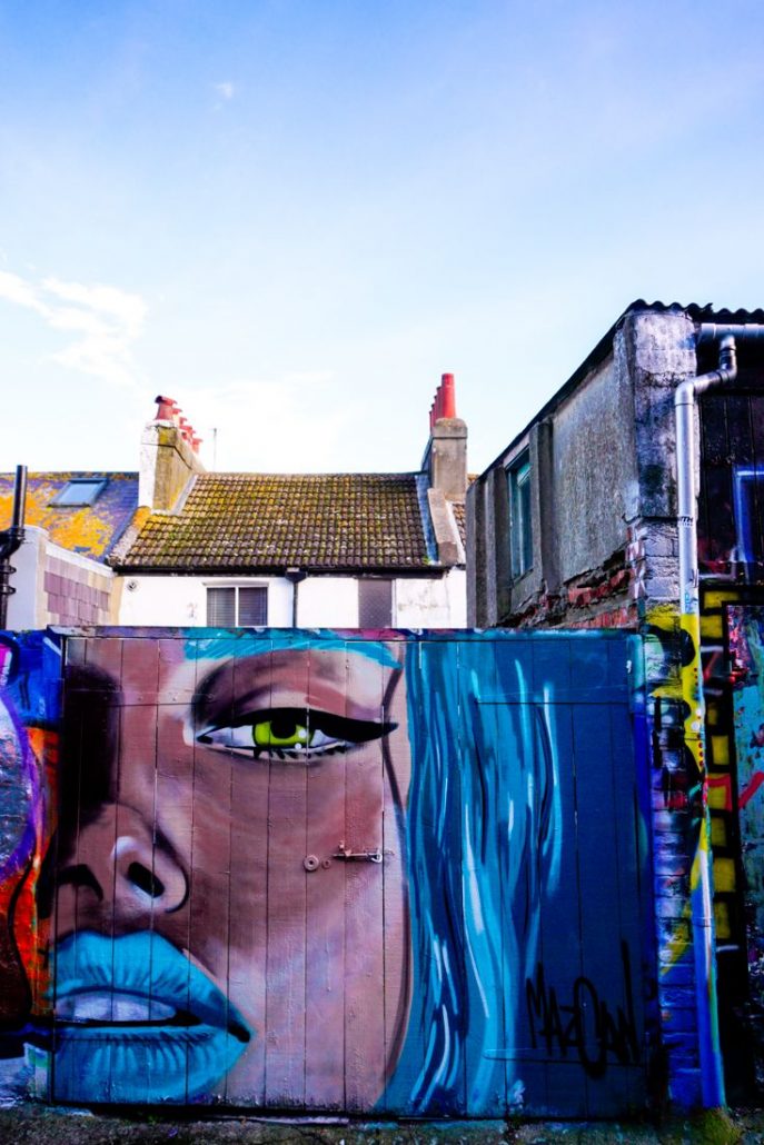 A street art piece of a woman with blue hair and blue lipstick